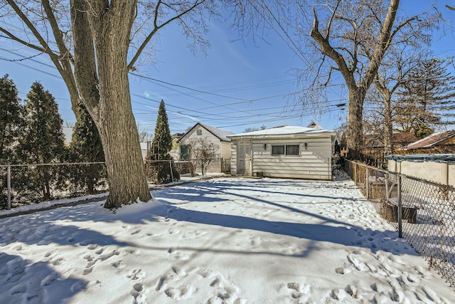 snow covered house with a fenced backyard and an outdoor structure