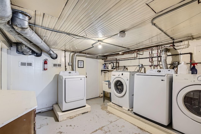 clothes washing area with laundry area, visible vents, and washing machine and clothes dryer