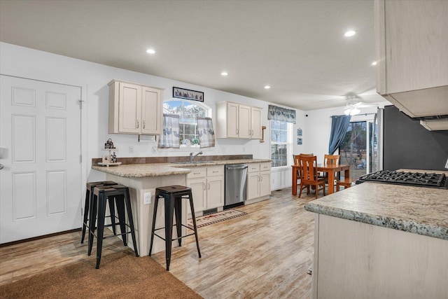 kitchen featuring light wood finished floors, ceiling fan, appliances with stainless steel finishes, and a breakfast bar area