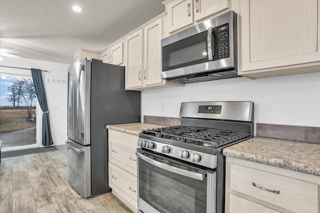 kitchen featuring light stone countertops, light wood finished floors, and stainless steel appliances