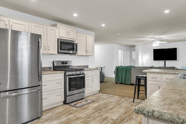 kitchen featuring light wood-style flooring, recessed lighting, stainless steel appliances, a ceiling fan, and open floor plan