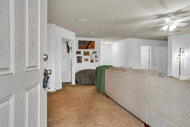 living room featuring carpet floors, visible vents, and a ceiling fan