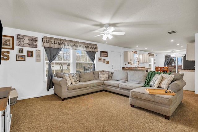 living room with light colored carpet, ceiling fan, and visible vents