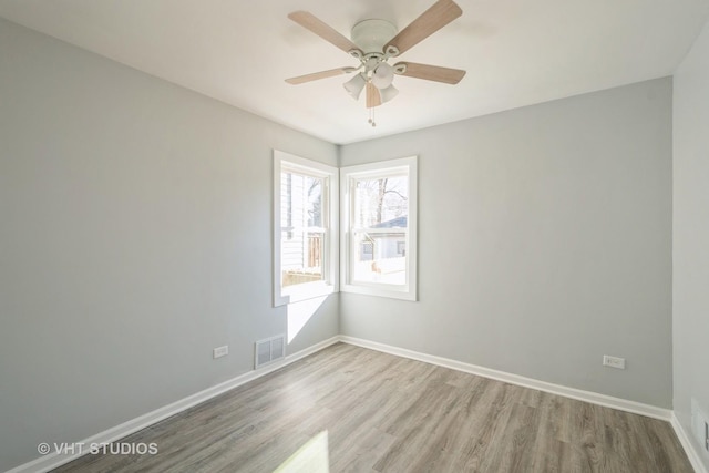 spare room with light wood-type flooring, baseboards, visible vents, and ceiling fan