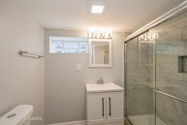 bathroom featuring vanity, a shower stall, and toilet