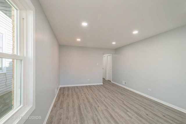 spare room featuring light wood-style flooring, recessed lighting, a wealth of natural light, and baseboards