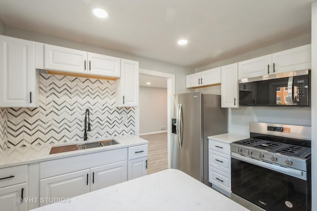 kitchen with appliances with stainless steel finishes, a sink, and white cabinets