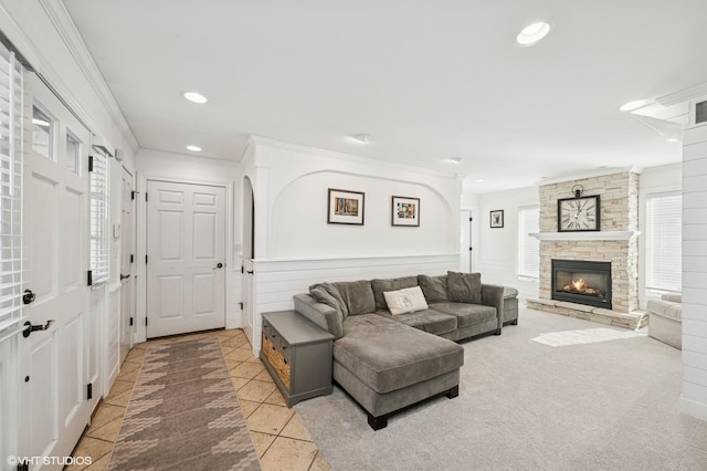 living area featuring ornamental molding, recessed lighting, a stone fireplace, and light tile patterned floors