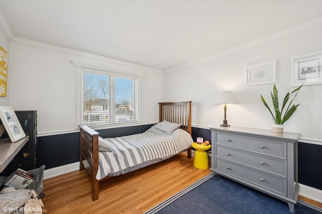 bedroom featuring baseboards, wood finished floors, and crown molding