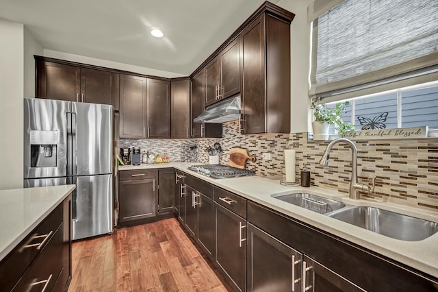 kitchen featuring dark wood-style floors, stainless steel appliances, light countertops, a sink, and under cabinet range hood