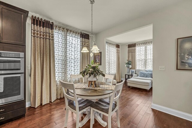 dining room with a notable chandelier, dark wood finished floors, and baseboards