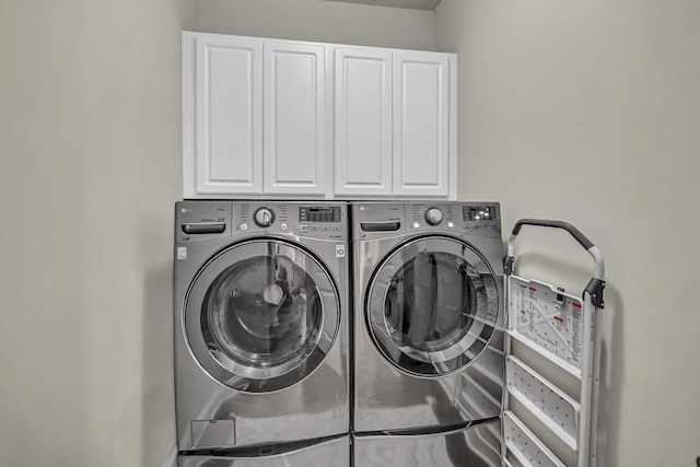 clothes washing area with washing machine and clothes dryer and cabinet space