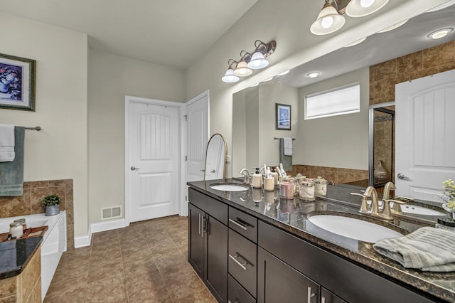 full bath with visible vents, a sink, a garden tub, and double vanity