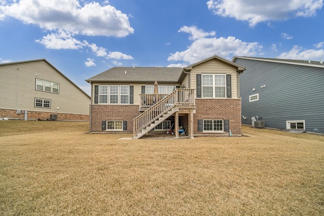 rear view of house with central AC, brick siding, a lawn, and stairs