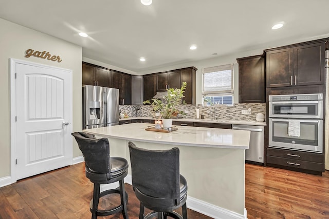 kitchen with dark brown cabinetry, appliances with stainless steel finishes, light countertops, and wood finished floors