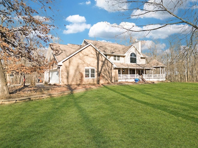 back of house with a porch, a yard, a chimney, and a garage