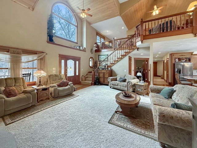 living room featuring stairs, ceiling fan, carpet flooring, and wood ceiling