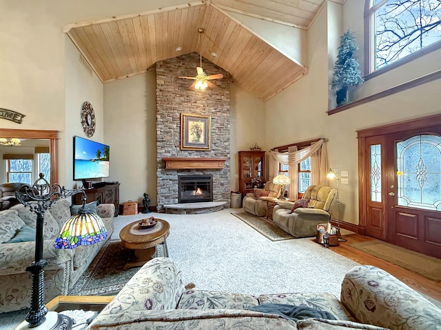 living area featuring a fireplace, visible vents, wood finished floors, high vaulted ceiling, and wooden ceiling