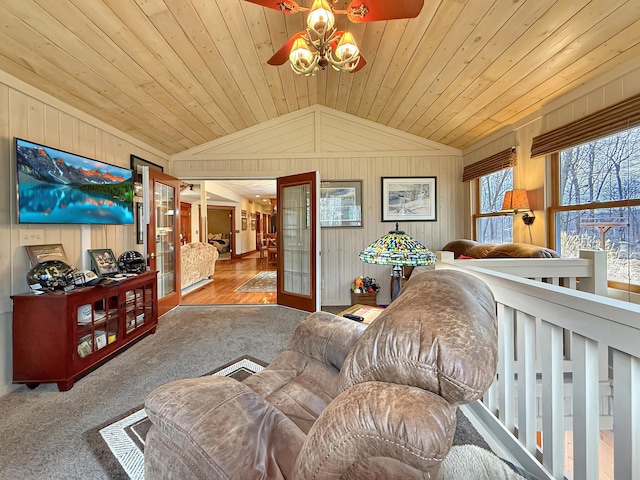 carpeted living room with lofted ceiling, wood walls, wood ceiling, and a ceiling fan