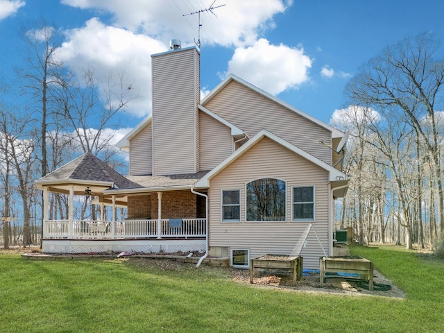 rear view of property with central air condition unit, a chimney, a porch, and a lawn