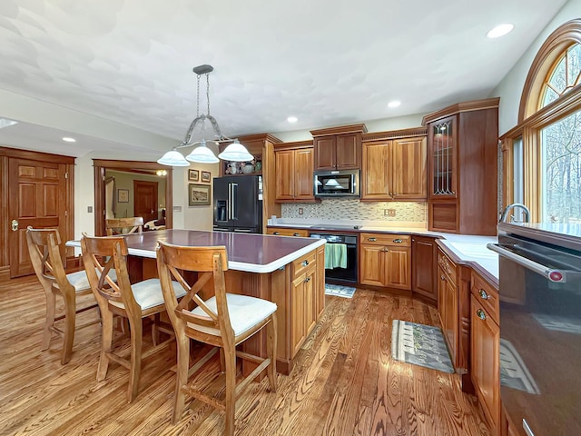 11307 Timber Lane Rd, Lena, IL 61048 - kitchen featuring black appliances, light wood-style flooring, a kitchen breakfast bar, a center island, and brown cabinets