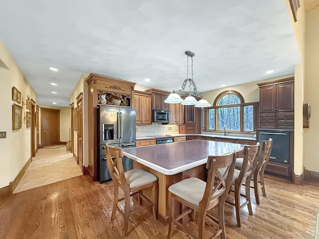 kitchen with stainless steel appliances, light wood-type flooring, backsplash, and a center island