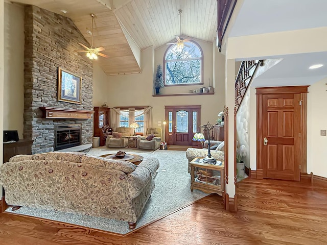 living room featuring wooden ceiling, ceiling fan, wood finished floors, a fireplace, and high vaulted ceiling