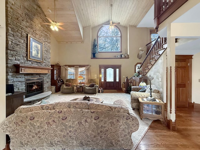 interior space with a stone fireplace, stairway, wood finished floors, and wood ceiling