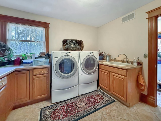 laundry area featuring washer and clothes dryer, light tile patterned floors, cabinet space, visible vents, and a sink