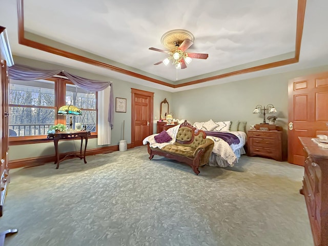 carpeted bedroom featuring a raised ceiling, a ceiling fan, and baseboards