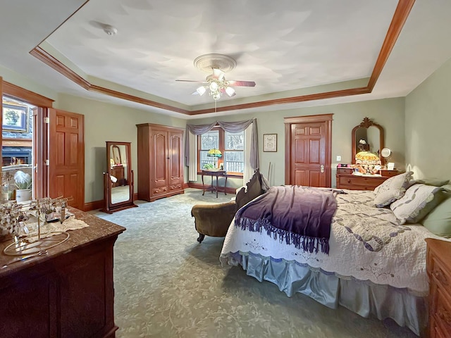 carpeted bedroom featuring a ceiling fan, a tray ceiling, and baseboards