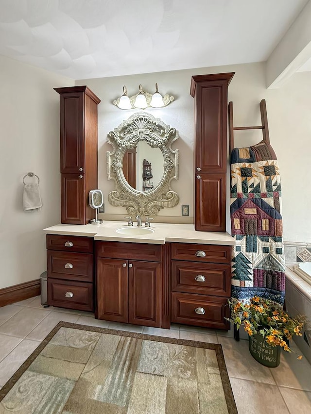 bathroom featuring tile patterned flooring, vanity, baseboards, and a bath