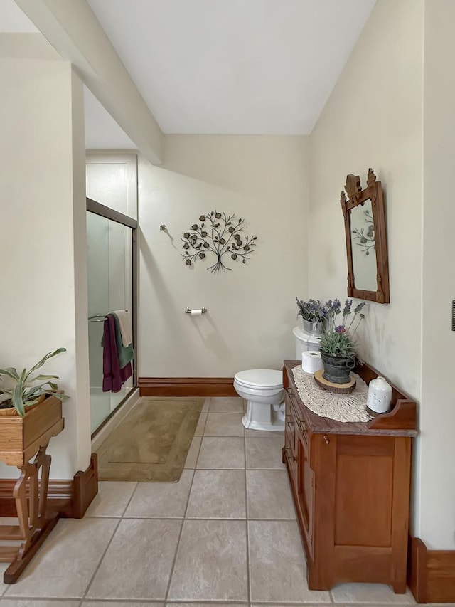 bathroom with toilet, vanity, baseboards, tile patterned floors, and a stall shower