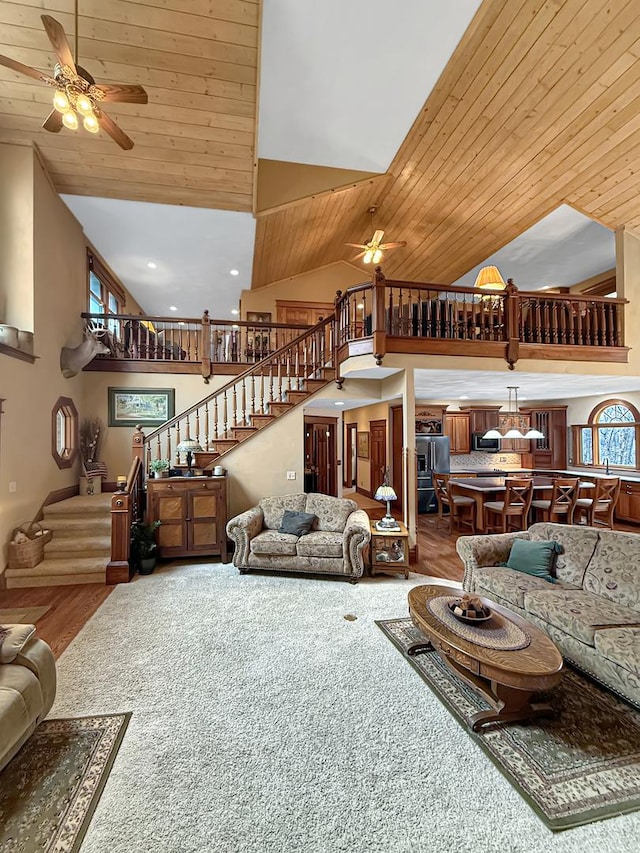 living room with ceiling fan, high vaulted ceiling, stairway, and wood ceiling