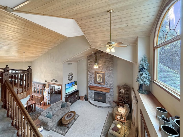 carpeted living area with high vaulted ceiling, a stone fireplace, and wooden ceiling