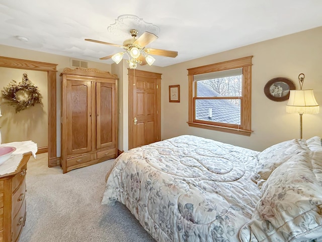 bedroom with ceiling fan, visible vents, and light colored carpet