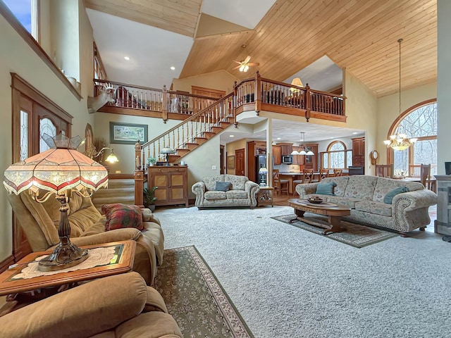 carpeted living room with high vaulted ceiling, wood ceiling, stairs, and a chandelier