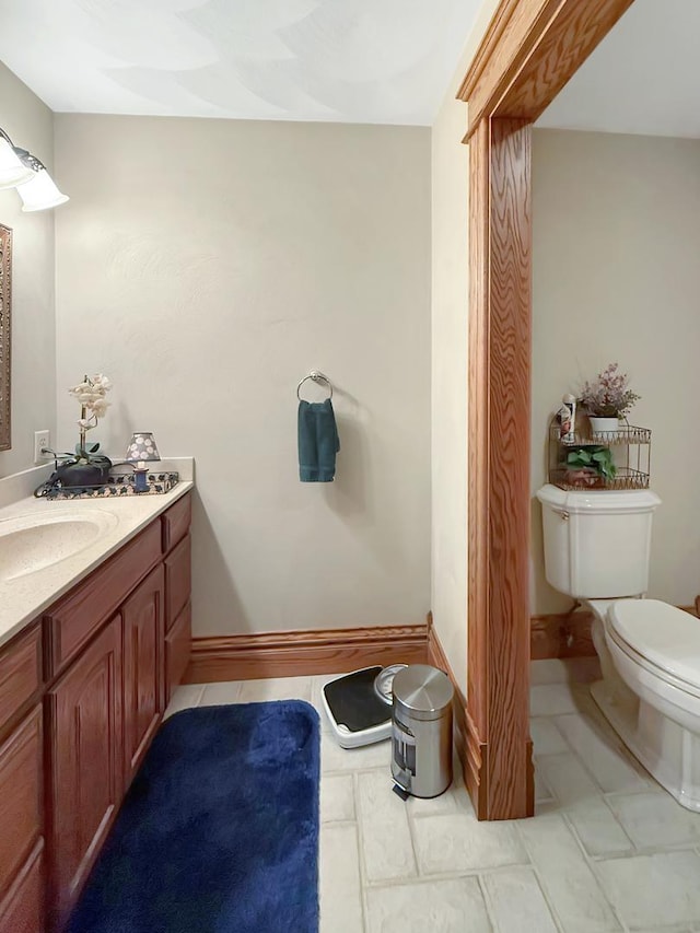 half bath with tile patterned flooring, baseboards, vanity, and toilet