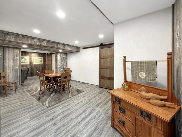 dining room featuring wooden walls, a barn door, light wood-style flooring, and recessed lighting