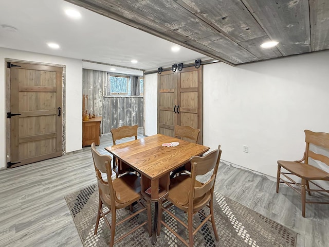 dining space with a barn door, light wood-style flooring, and recessed lighting