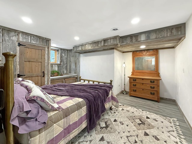 bedroom with baseboards, wood finished floors, visible vents, and recessed lighting