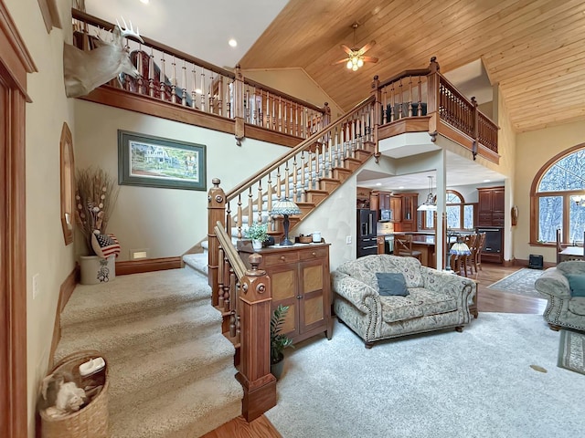 stairway featuring high vaulted ceiling, carpet floors, wooden ceiling, and baseboards