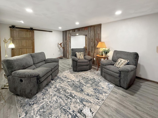 living room featuring recessed lighting, wood finished floors, baseboards, and a barn door