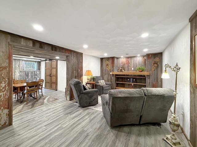 living room with light wood-type flooring, wood walls, and recessed lighting