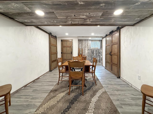 dining room featuring light wood-type flooring, a barn door, and baseboards