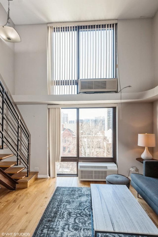 unfurnished living room with stairway, wood finished floors, and a towering ceiling