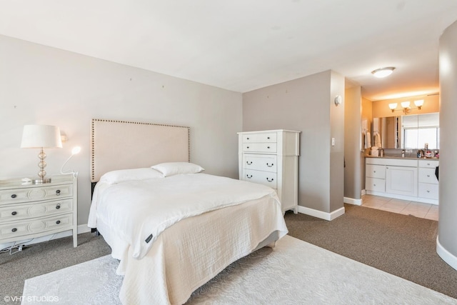 bedroom with baseboards, ensuite bathroom, and light colored carpet