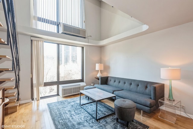 living area with light wood-type flooring, a towering ceiling, and baseboards