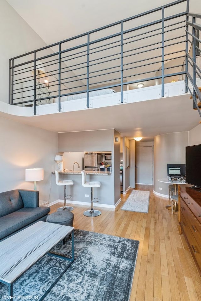 living room with wood finished floors, a towering ceiling, and baseboards