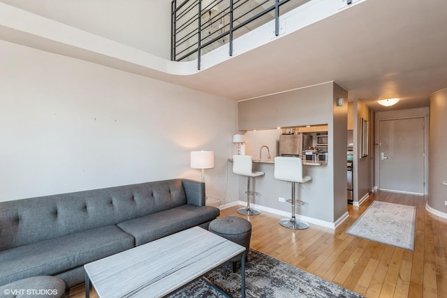 living area featuring a high ceiling, baseboards, and wood finished floors